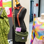 Es stehen drei Modepuppen nebeneinander. Diese tragen selbstgenähte Kleidung und Accessoires. Links in Camouflage. Mitte: Accessoires aus Kletterseil. Rechts: Regenbogenfarbener Sportbody.