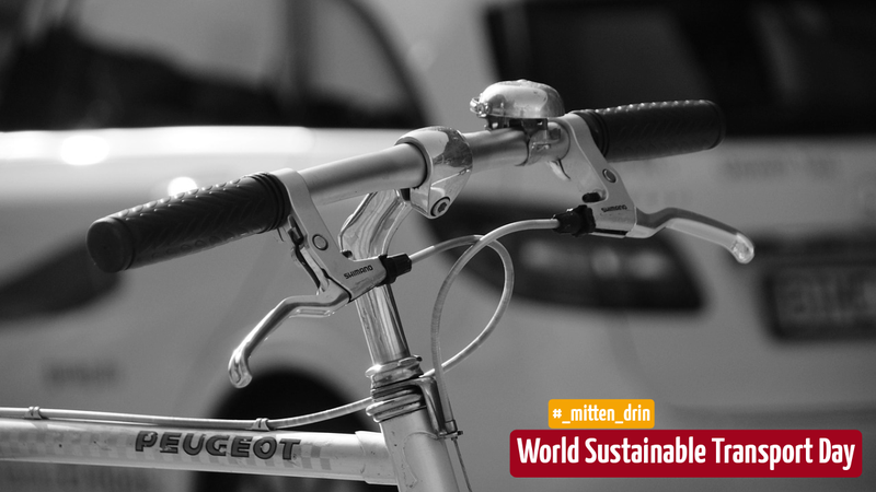 Das Bild zeigt einen Nahaufnahme des Lenkers eines Fahrrads mit einem Peugeot-Logo. Die Schwarz-Weiß-Aufnahme hebt die Fahrradgriffe und Bremshebel hervor. In der Ecke des Bildes befindet sich ein Hinweis auf den Welt-Tag für nachhaltigen Transport.