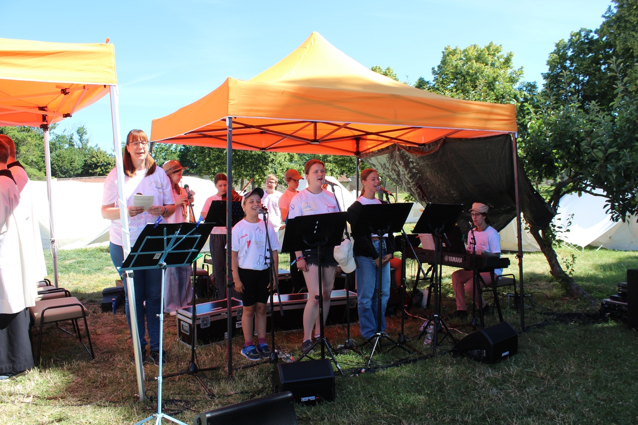Kinder und Jugendliche, die unter einem Pavillon singen und Instrumente spielen