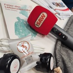 Nahaufnahme eines Stehtisches, Mikrofon von Radio SAW, Glückskeksverpackung, Fahrradklingel und Flyer liegen auf dem Tisch.