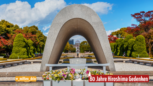 Das steinerne Kenotaph für die Opfer der Atombombe, steht zentral in der Mitte, davor sind Blumen zu sehen, rechts und links umrahmen die Gedenkstätte große Bäume. Darauf der Schriftzug: #mitten_drin und 80 Jahre Hiroshima Gedenken mit einer Friedenstaube