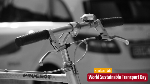 Das Bild zeigt einen Nahaufnahme des Lenkers eines Fahrrads mit einem Peugeot-Logo. Die Schwarz-Weiß-Aufnahme hebt die Fahrradgriffe und Bremshebel hervor. In der Ecke des Bildes befindet sich ein Hinweis auf den Welt-Tag für nachhaltigen Transport.