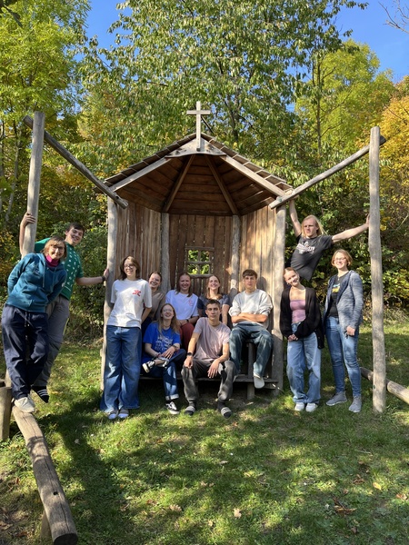 In einer kleinen Holzhütte und auch drumherum sind die jungen Menschen zu sehen