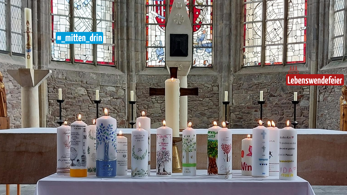 Auf dem Foto ist ein Tisch vor dem Altar in einem Kirchenraum zu sehen, darauf befinden sich selbstgestaltete Kerzen, die angezündet sind.