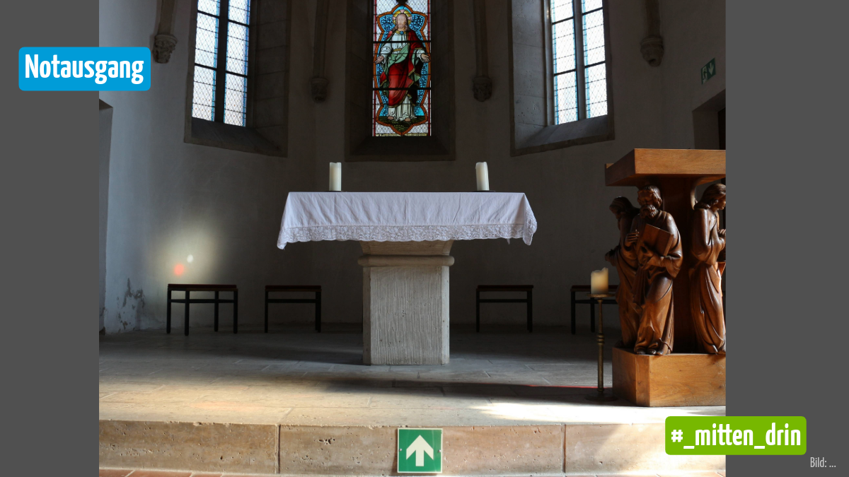 Apsis in einer Kirche, der Altar steht in der Mitte, auf der Stufe zum Altar ist ein Schild mit einem Pfeil angebracht
