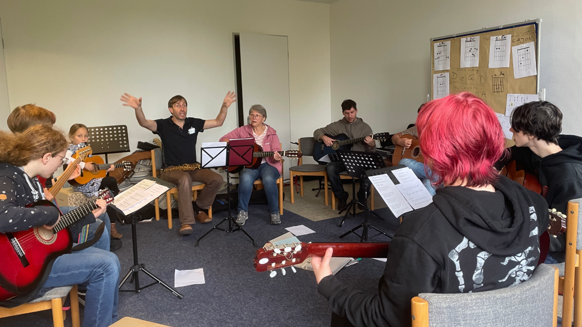 Eine Person erklrät im Stuhlkreis das Gitarrenspiel.
